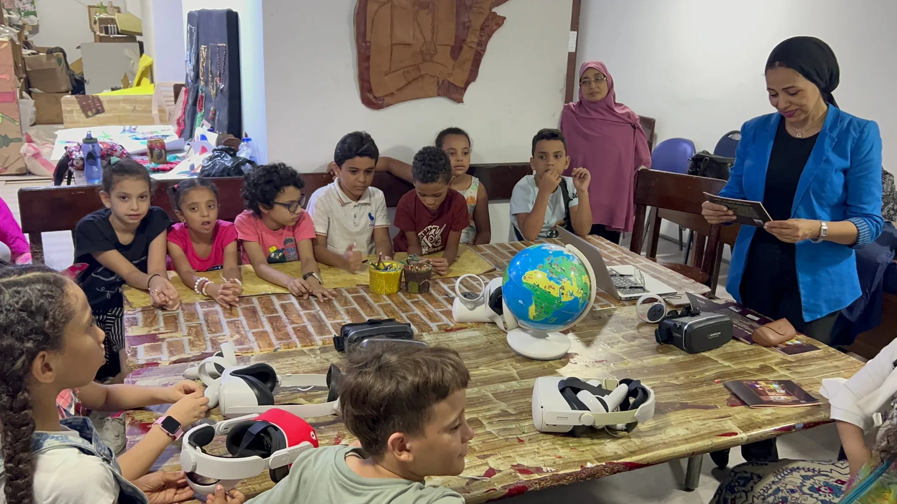 أطفال مبادرة «بداية جديدة» حول طاولة نظارات الواقع الافتراضي في المتحف المصري